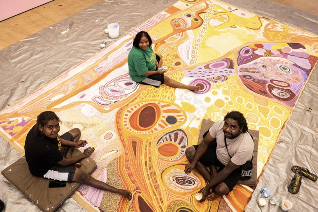 Martumili Artists Martumili Artists painting on a large colourful canvas